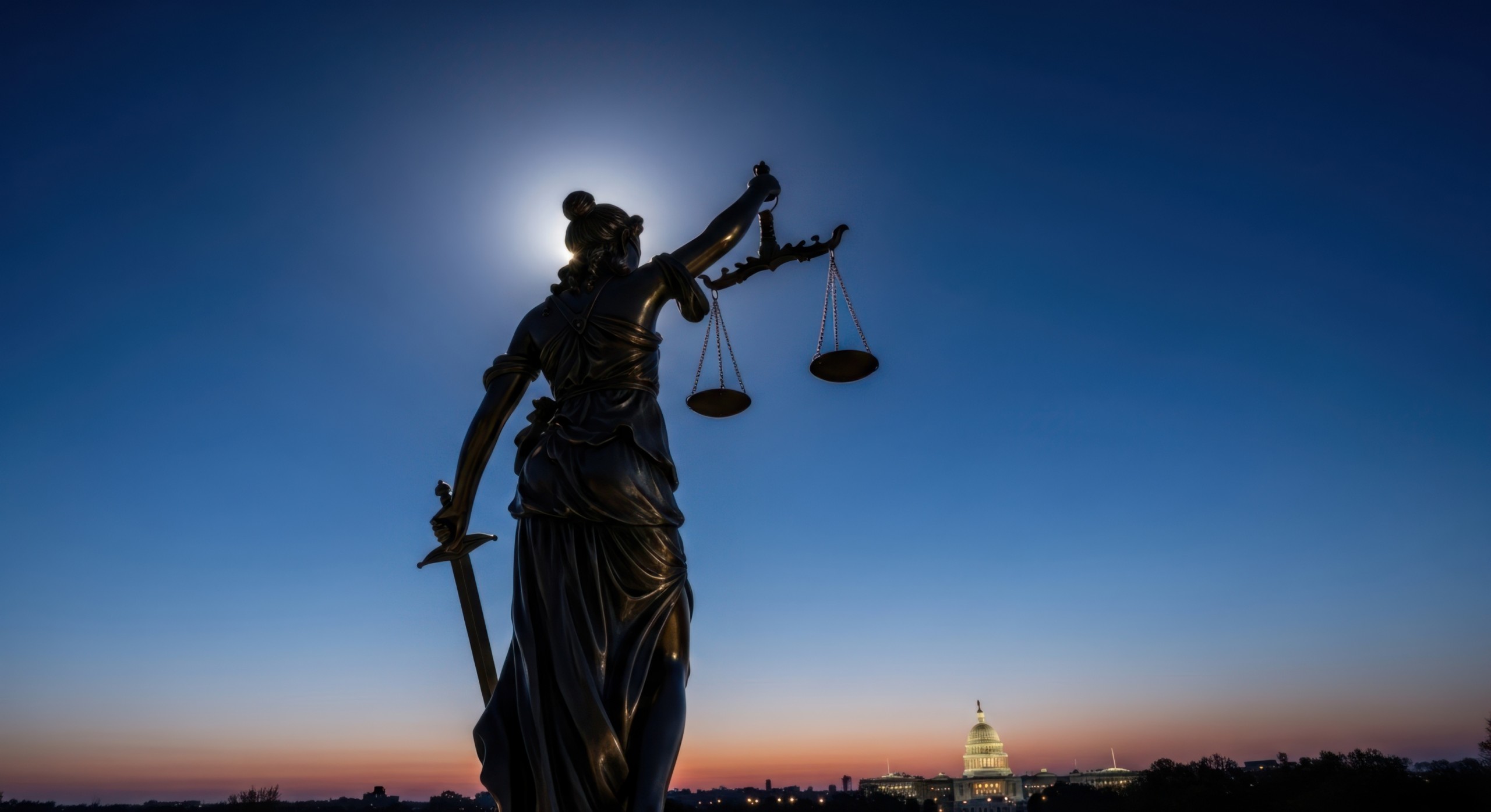 Lady justice statue silhouetted at dusk with capitol building in background, symbolizing law